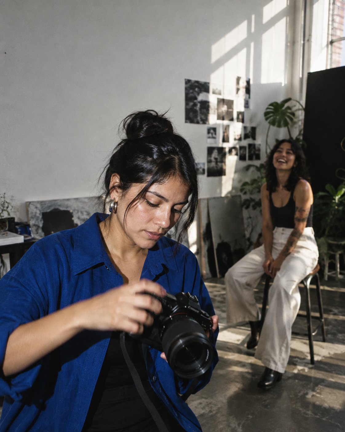 Una fotógrafa prepara una sesión con una persona en el estudio.